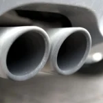 A car exhaust tailpipe being inspected for a popping noise fault