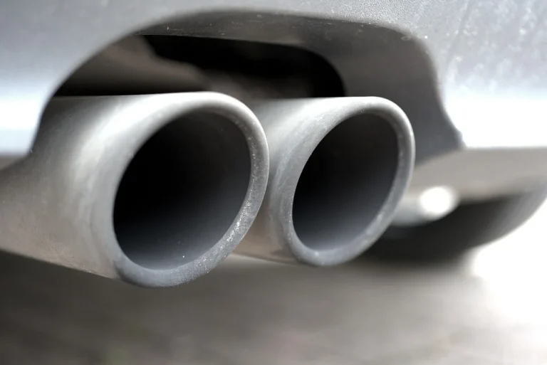 A car exhaust tailpipe being inspected for a popping noise fault