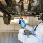 Mechanic inspecting the underbody structure of a car for corrosion during an MOT check