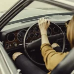 A driver changing gear smoothly with the fuel gauge visible on the dashboard
