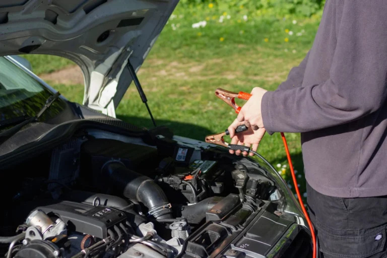 Mechanic checking a car battery and antifreeze levels in winter