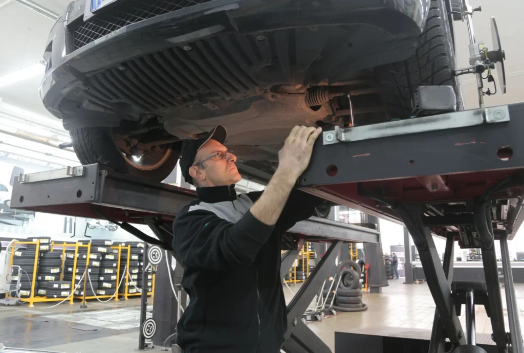 Mechanic inspecting the underside of a car during a pre-purchase check