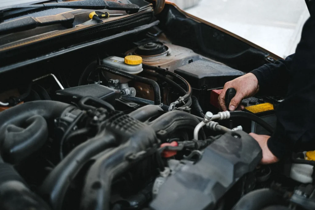 Mobile mechanic checking under the bonnet of a car on a driveway
