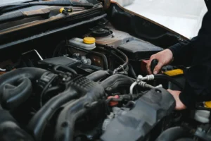 Mobile mechanic checking under the bonnet of a car on a driveway