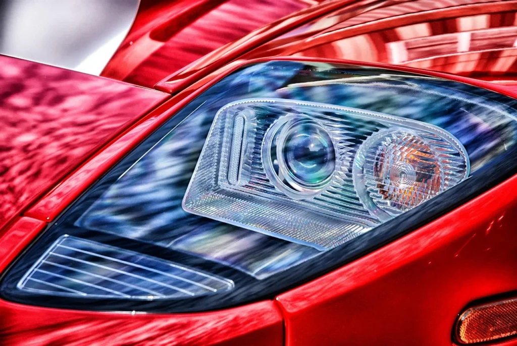 A driver replacing a headlight bulb by hand in the engine bay of a car
