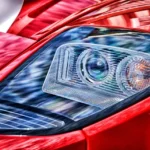 A driver replacing a headlight bulb by hand in the engine bay of a car