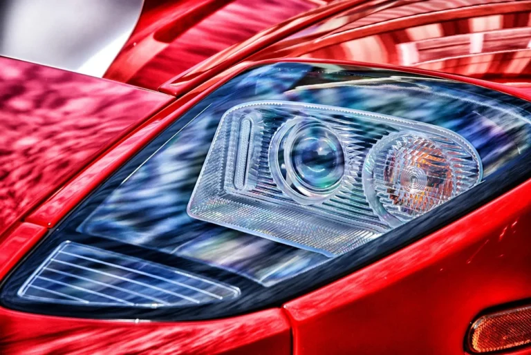 A driver replacing a headlight bulb by hand in the engine bay of a car