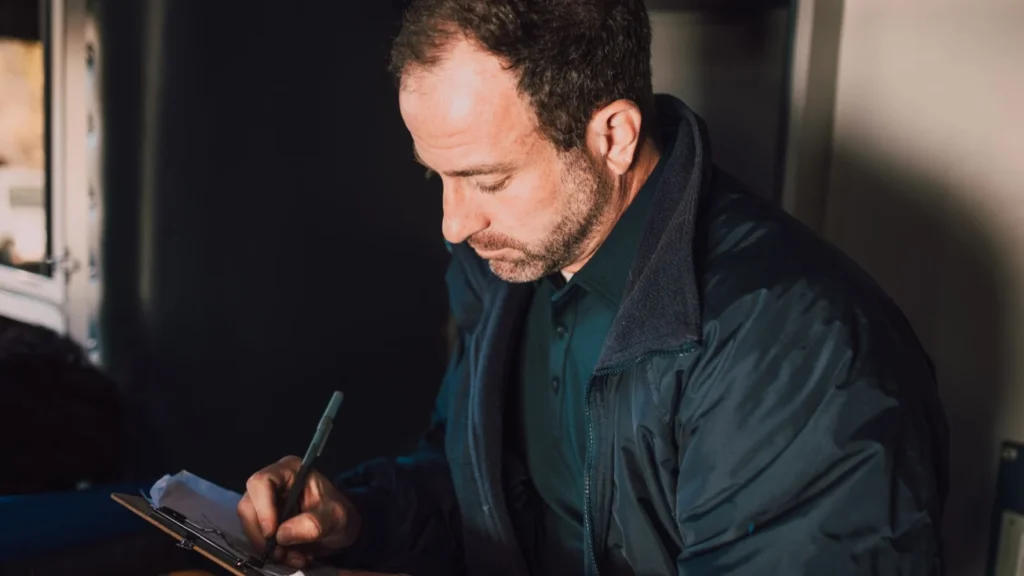 Adult male writing notes on a clipboard inside. Concentrated and thoughtful atmosphere — SSK Mechanics guide to Audi A3 Service and MOT Checklist by Powertrain