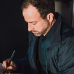 Adult male writing notes on a clipboard inside. Concentrated and thoughtful atmosphere — SSK Mechanics guide to Audi A3 Service and MOT Checklist by Powertrain