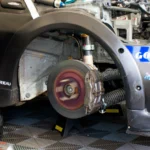 Close-up of race car undergoing maintenance in Silverstone, showing disc brake and tools — SSK Mechanics guide to Vauxhall Corsa Brake Pads, Discs and Calipers Guide