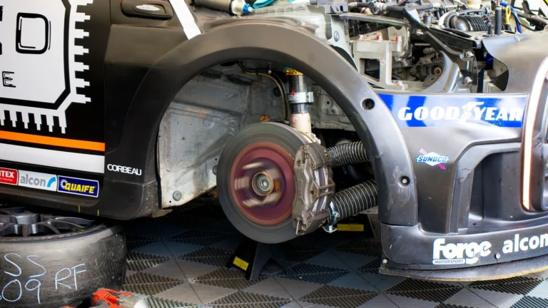 Close-up of race car undergoing maintenance in Silverstone, showing disc brake and tools — SSK Mechanics guide to Vauxhall Corsa Brake Pads, Discs and Calipers Guide