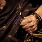 Close-up view of a mechanic's hands working on a car engine with a wrench in an industrial setting — SSK Mechanics guide to Nissan Qashqai Oil Change or Full Service