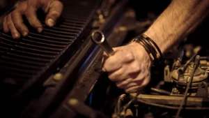 Close-up view of a mechanic's hands working on a car engine with a wrench in an industrial setting — SSK Mechanics guide to Nissan Qashqai Oil Change or Full Service