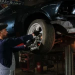 A focused mechanic works on a car wheel in a dimly lit garage, showcasing automotive repair skills — SSK Mechanics guide to MINI Hatch Brake Pads, Discs and Calipers Guide