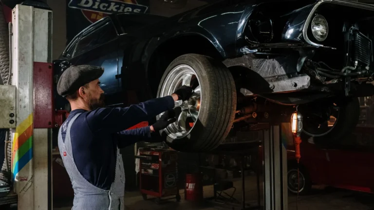 A focused mechanic works on a car wheel in a dimly lit garage, showcasing automotive repair skills — SSK Mechanics guide to MINI Hatch Brake Pads, Discs and Calipers Guide
