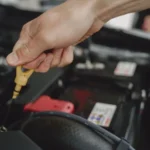 Hand checking oil dipstick in a car engine bay for maintenance and diagnostics — SSK Mechanics guide to Vauxhall Astra Oil Change or Full Service