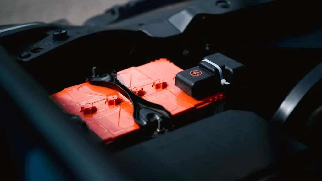 Detailed view of an orange car battery inside a vehicle's engine bay, highlighting its features — SSK Mechanics guide to Toyota Yaris Battery Check and Car-Not-Starting Guide