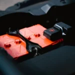 Detailed view of an orange car battery inside a vehicle's engine bay, highlighting its features — SSK Mechanics guide to Toyota Yaris Battery Check and Car-Not-Starting Guide