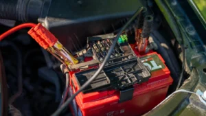 Close-up view of a car battery with red jumper cables connected, outdoors — SSK Mechanics guide to Fiat 500 Battery Check and Car-Not-Starting Guide