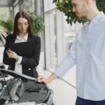 Man and woman examining car engine in dealership service area, focused on vehicle maintenance… — SSK Mechanics guide to BMW 1 Series Oil Change or Full Service