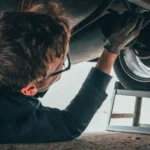 Mechanic skillfully repairing car undercarriage in outdoor setting with tools — SSK Mechanics guide to Mercedes A-Class Brake Pads, Discs and Calipers Guide