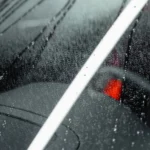 Close-up of a car windshield with water droplets creating an abstract pattern under light — SSK Mechanics guide to Renault Clio Wipers, Bulbs and Fuse Changes