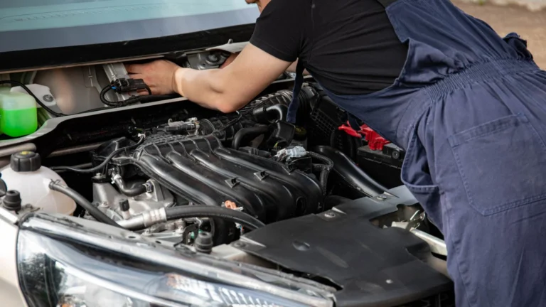 Mechanic in blue overalls repairing a car engine under the hood outdoors — SSK Mechanics guide to Hyundai Tucson Battery Check and Car-Not-Starting Guide