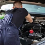 Mechanic in blue coveralls performing car engine maintenance outdoors — SSK Mechanics guide to Car Won't Start? Battery, Starter, Alternator or Something Else