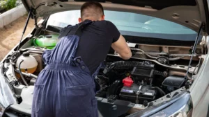 Mechanic in blue coveralls performing car engine maintenance outdoors — SSK Mechanics guide to Car Won't Start? Battery, Starter, Alternator or Something Else