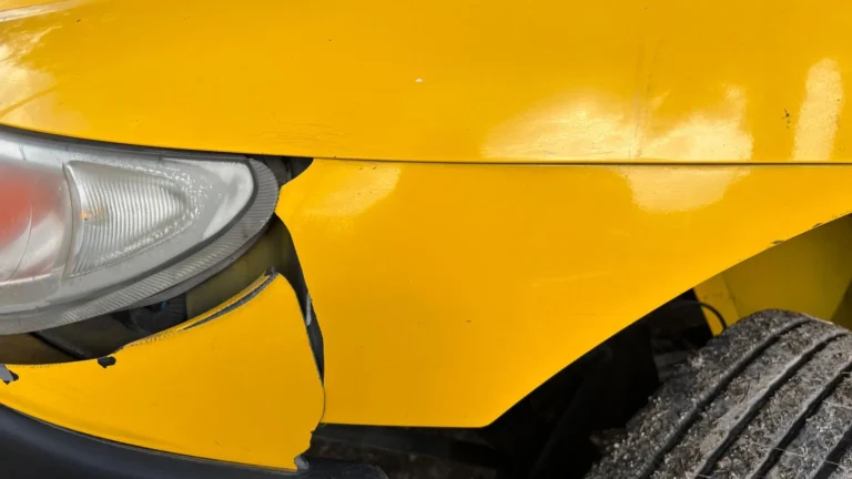 Close-up of dented yellow car bodywork after impact damage