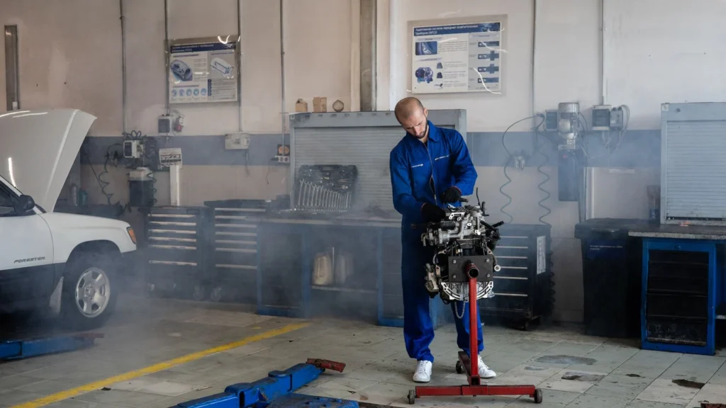 A mechanic repairing a car engine in a busy auto repair shop with tools around — SSK Mechanics guide to Burning Smell From the Engine Bay: What Should I Check
