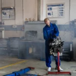 A mechanic repairing a car engine in a busy auto repair shop with tools around — SSK Mechanics guide to Burning Smell From the Engine Bay: What Should I Check