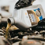 Close-up of a mechanic pouring engine oil into a car engine, highlighting maintenance work — SSK Mechanics guide to Oil Leak Under the Car: What Could Be Causing It