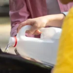 Close-up of hands pouring water into a car engine, focusing on auto maintenance — SSK Mechanics guide to Coolant Leak Under the Car: What's the Likely Cause