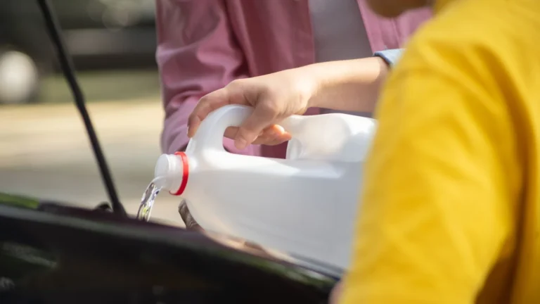 Close-up of hands pouring water into a car engine, focusing on auto maintenance — SSK Mechanics guide to Coolant Leak Under the Car: What's the Likely Cause