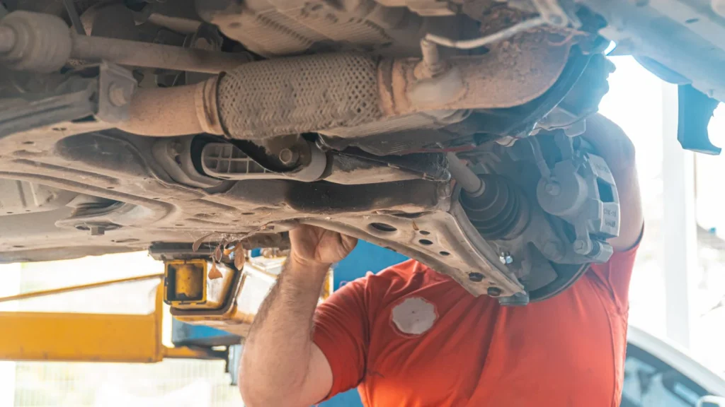 Mechanic working under a vehicle, inspecting the undercarriage in a repair garage, ensuring… — SSK Mechanics guide to Why Is My Brake Pedal Sinking to the Floor