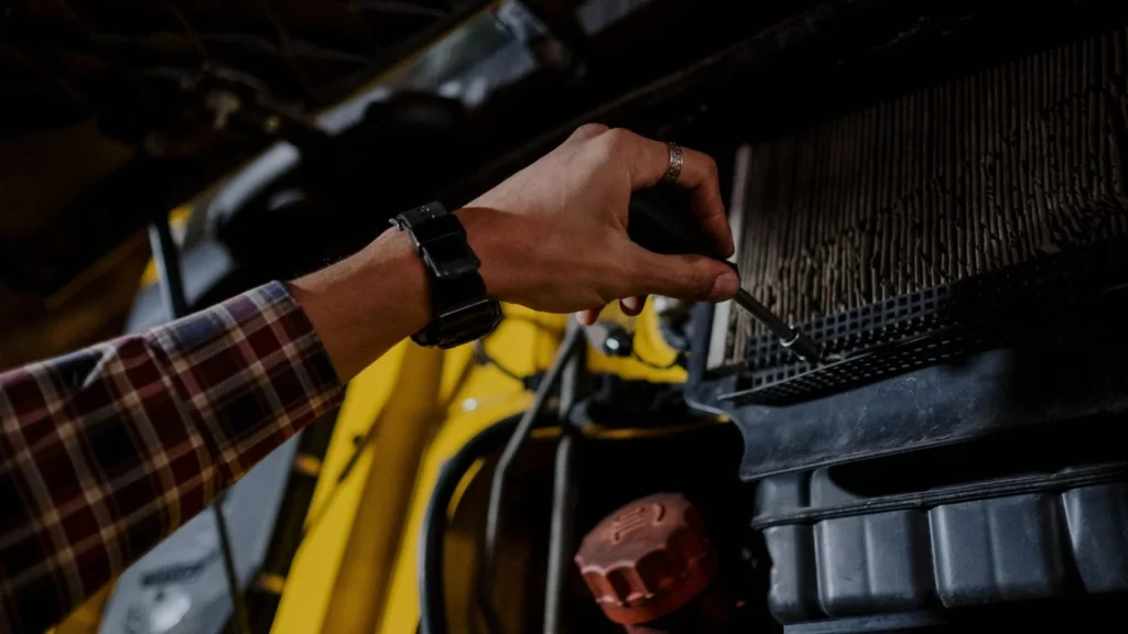 Close-up of a mechanic's hand using a screwdriver to inspect a vehicle's engine — SSK Mechanics guide to Coolant Temperature Warning Light: What It Means and What to…