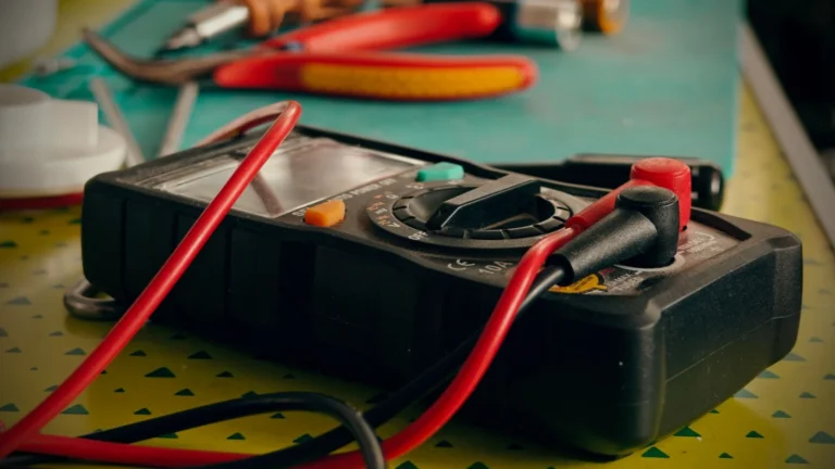 Close-up view of a multimeter and various tools on a workspace table — SSK Mechanics guide to Battery Warning Light On: What It Means and How Urgent It Is