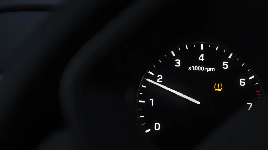 A detailed view of a car tachometer showing RPM with tire pressure warning — SSK Mechanics guide to EV Warning Light On: What It Means and When to Stop Driving