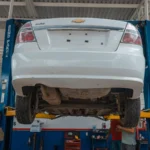 A white Chevrolet car is lifted for maintenance in an automotive repair shop — SSK Mechanics guide to How Mobile MOT Collection and Return Works