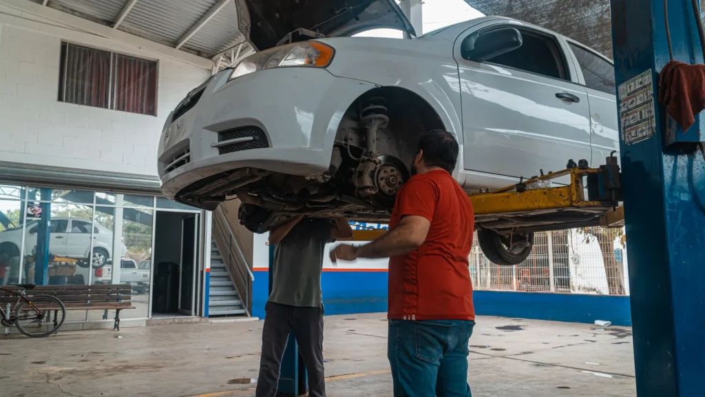 Two mechanics inspecting a white car on a lift inside a garage workshop — SSK Mechanics guide to How Often Should You Service Your Car? A UK Guide