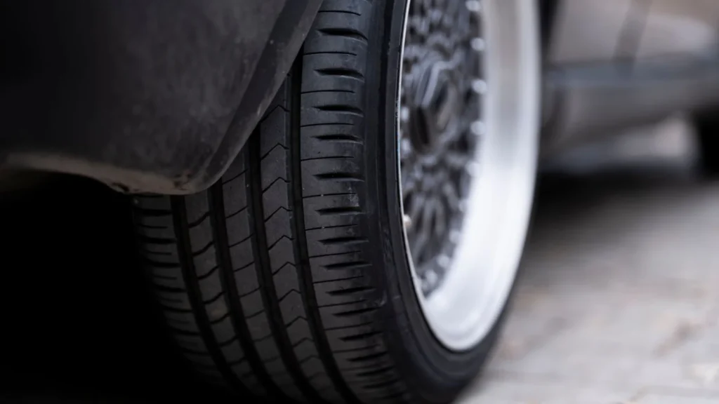 Detailed view of a car tire on urban pavement, showcasing tread and wheel design — SSK Mechanics guide to Your Pre-Long-Journey Car Checklist