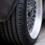 Detailed view of a car tire on urban pavement, showcasing tread and wheel design — SSK Mechanics guide to Your Pre-Long-Journey Car Checklist