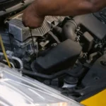 Driver carrying out an under-bonnet maintenance check outdoors — SSK Mechanics guide to extending the life of your car