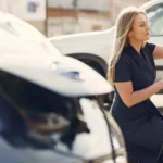 Side view of full length female driver in casual dress squatting near station while charging… — SSK Mechanics guide to Electric & Hybrid Car Maintenance: What Actually Needs Servicing