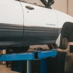 Mechanic evaluating a car on a lift for maintenance in an auto workshop — SSK Mechanics guide to Do Electric and Hybrid Cars Still Need Brake Fluid Changes