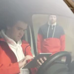 A man in a red jacket uses a tablet inside a car as seen through the windshield — SSK Mechanics guide to What Does It Really Cost to Own a Car? The Main Factors Explained