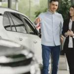 Customer and salesperson discussing a vehicle inside a modern car dealership showroom — SSK Mechanics guide to How Many Miles Is Too Many? Understanding High Mileage Cars