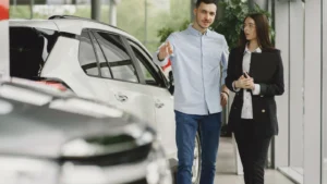 Customer and salesperson discussing a vehicle inside a modern car dealership showroom — SSK Mechanics guide to How Many Miles Is Too Many? Understanding High Mileage Cars