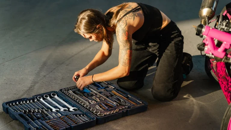 Young tattooed woman in black tank top organizing tools from a toolbox beside a motorcycle — SSK Mechanics guide to What to Expect When a Mobile Mechanic Comes to You